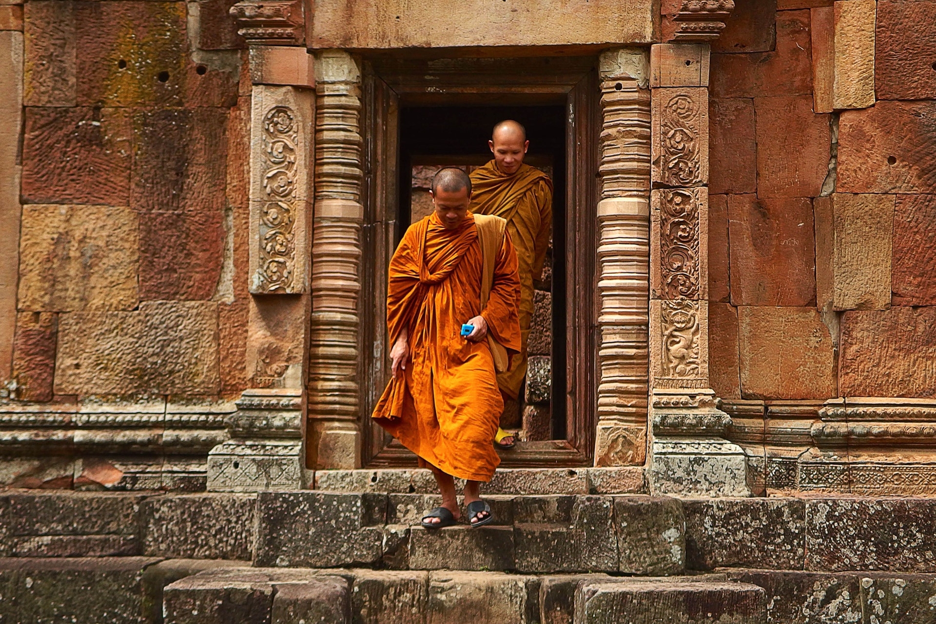 two-monk-in-orange-robe-walking-down-the-concrete-stairs
